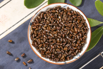 Traditional Chinese Cassia Seeds for Herbal Tea in Ceramic Bowl on Wooden Background