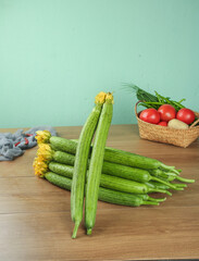 Fresh Loofah Shandong Vegetables Bundle on Wooden Kitchen Table with Organic Produce Basket