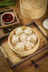 Traditional Chinese Siu Mai Dumplings in Bamboo Steamer with Chopsticks and Sauce