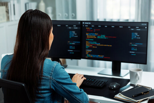 Young Asian in IT developer creating with typing online information on pc with coding program data of website application, wearing jeans shirt. surrounded by safety analysis two screens. Stratagem.