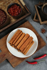 Long Natural Cinnamon Sticks from Guangxi China with Traditional Spices and Chili Peppers on Rustic Kitchen Counter