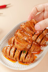 Hand picking up glazed braised pork belly slices from plate - traditional Asian homemade cuisine