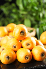 Fresh Loquat Fruits from Yunnan China in Wooden Basket with Green Background