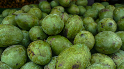 Piles of fresh mangoes during harvest season. Organic green mangoes at the fruit store.