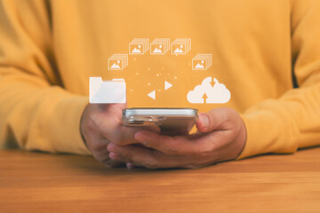 Hands holding a smartphone with icons of folders, images, and cloud upload, representing digital file transfer, cloud storage, mobile backup, data management, and seamless multimedia synchronization.
