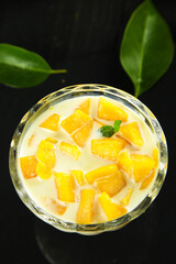 Fresh Mango Dessert with Cream and Tropical Fruit Pieces in Glass Bowl