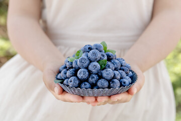 Woman holding bowl of fresh blueberries - healthy organic fruit berries in hands