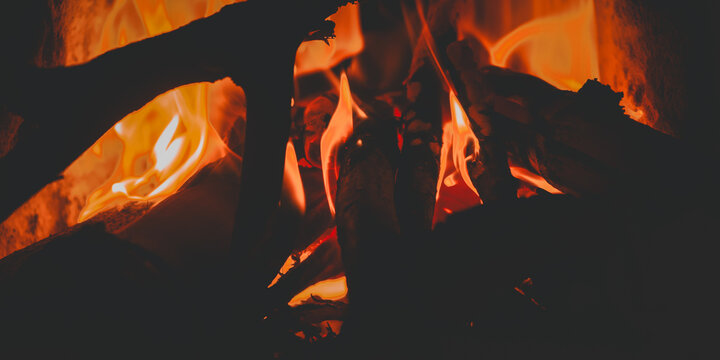 The fire from the wood burned brightly in the darkness, emitting a warm orange and yellow glow. - Powered by Adobe