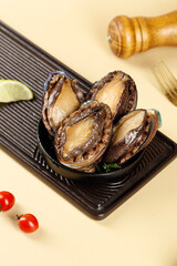Closeup of Fresh Seared Abalone Shellfish on Grill Plate with Lime and Tomatoes Premium Seafood Ingredients