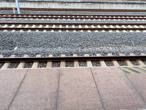 Multiple Parallel Train Tracks Stretching into the Distance from a Station Platform, Showcasing Railway Infrastructure with Ballast and Concrete Sleepers