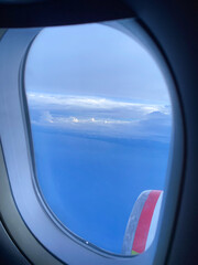 Fototapeta premium Stunning Aerial View from an Airplane Window Showcasing Vast Blue Sky, White Clouds, and a Part of the Aircraft Engine During a Peaceful Flight