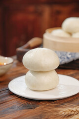 Fresh Handmade Steamed Buns on Plate with Traditional Bamboo Steamer Basket on Wooden Table