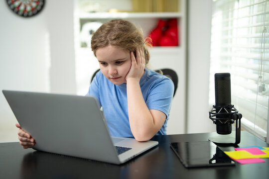 Child typing on a laptop during learning. Kids education at home. Child learning at home using a laptop. Kid learning schoolwork at home. Kid focusing on online learning at the desk. - Powered by Adobe