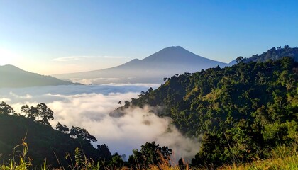 Majestic mountain landscape with clouds and lush greenery at sunrise.