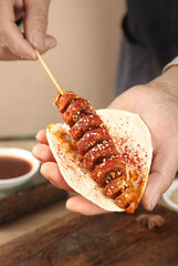 Grilled Spiced Meat Skewer on Wooden Stick with Sesame Seeds in Paper Wrapper - Homemade Street Food