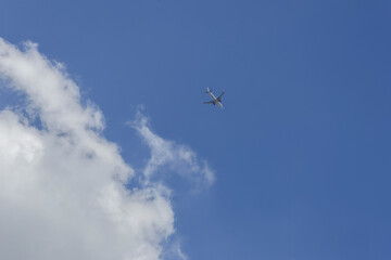 Commercial airplane on high flight through vast blue sky. serene journey offering sense of freedom, aircraft traveling above fluffy white cloud