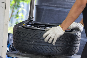 Focused mechanic in garage performing tire repair service with machine. worker with gloves working on rubber wheel for vehicle maintenance and transportation