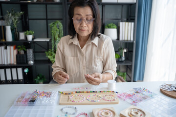 Fototapeta premium Senior mature older asian woman Art hobby handmade making beads jewellery accessories handcraft hobby