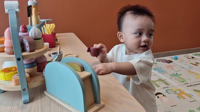 A cute little child smiles happily while playing with toys made from wood and non-toxic paint to enhance their development.