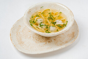 Warm soup filled with noodles and herbs sits invitingly in a handmade bowl, ready to enjoy
