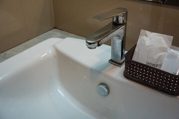 Close up of a faucet and white ceramic sink, minimalist bathroom