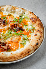 A gourmet seafood pizza features shrimp, octopus, and vibrant herbs on a golden crust