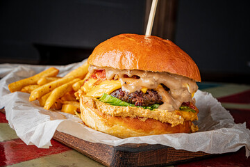 A mouthwatering burger with layers of cheese, bacon, and fresh lettuce sits beside golden fries