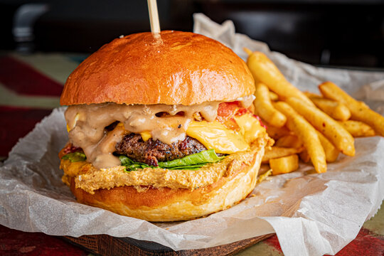 A hearty cheeseburger topped with fresh ingredients and creamy sauce alongside crispy fries