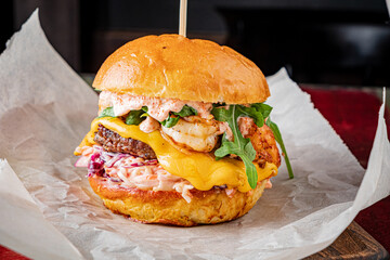 Tasty burger with shrimp, melted cheese, and greens served in a cozy atmosphere
