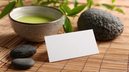 Blank white business card template on bamboo mat with zen stones and green tea ceremony setup