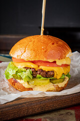 A delicious cheeseburger layered with cheese, lettuce, tomato, and pickles ready to be enjoyed