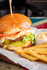 A mouthwatering burger towers with fresh ingredients, paired with crispy fries and sauce