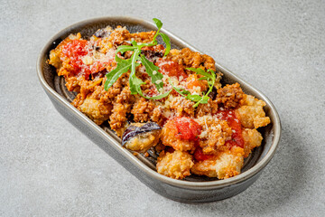 Crispy fried dish covered in rich tomato sauce and herbs, served on a stylish gray plate