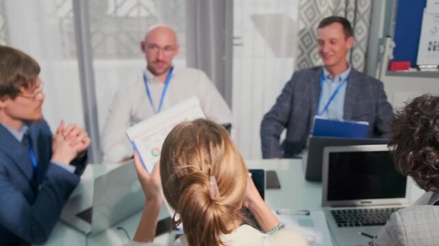 In a modern office, a financial consultant in a blue suit gives colleagues practical legal and financial advice on boosting company promotion, increase in profits and cutting expenses. 