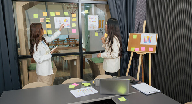 Business women meet, busy team people work on project, meeting for planning business strategy, woman pointing data charts for presentation, collaboration in modern office - Powered by Adobe