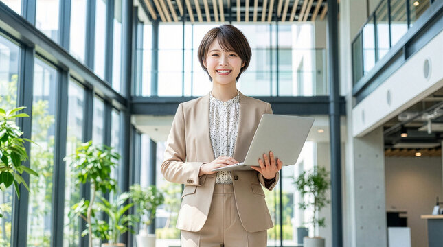 ノートパソコンを持つカジュアルスーツを着た笑顔の女性