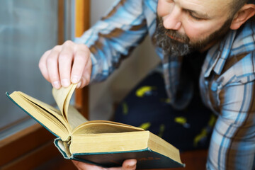 Man Reading Old Book: Relaxed Home Setting Captured in a Candid Moment