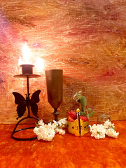 Lilac flowers, strawberries. Evening romantic still life on a red background, candle in a candlestick. Romance, flowers, elegance, flair. Antique brass items