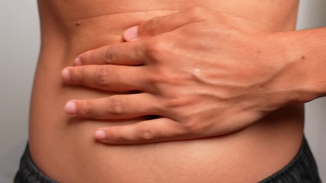 A hand rests on the abdomen, performing a circular clockwise massage around the navel to aid digestion, ease bloating, improve comfort, promote wellness, and enhance relaxation and self-care.
