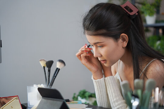 Asian woman influencer beauty blogger live streaming reviews her cosmetics on online platform