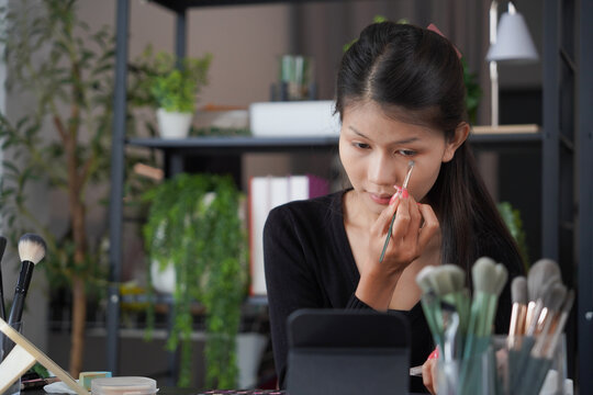 Asian woman influencer beauty blogger live streaming reviews her cosmetics on online platform