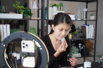 Asian woman influencer beauty blogger live streaming reviews her cosmetics on online platform