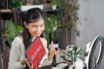 Asian woman influencer beauty blogger live streaming reviews her cosmetics on online platform