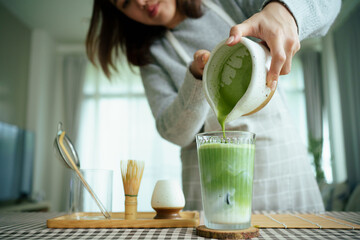 Naklejka premium Barista pouring matcha into iced milk to make a layered matcha latte.