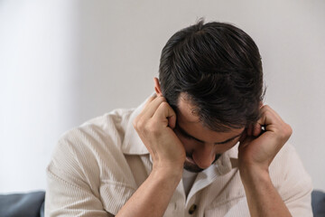 Sad anxious man feeling stress and depression while sitting alone on sofa, suffering emotional problem and mental frustration at home