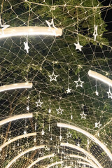 Strings of tiny star lights hang across curved frames in a bright display, and the glowing ornaments form a striking pattern over the walkway.