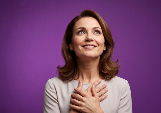 A portrait of a woman filled with gratitude, with her hands over her heart and her eyes gazing upwards.