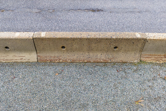 Curbstone Barrier Along a Rough Roadside in BC, Canada With Asphalt and Gravel