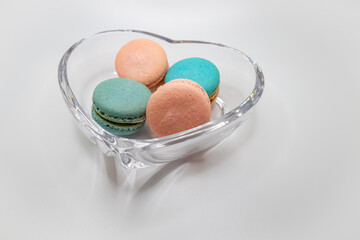 Macro studio shot of pink and blue green sweet macaron cookies in a crystal bowl, on white background with copy space
