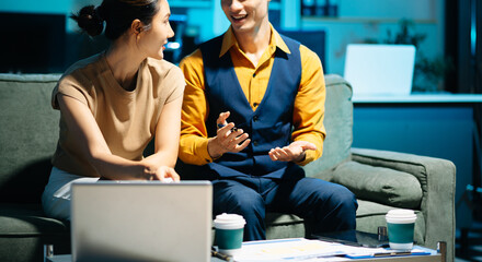 Asian couple working together with a tablet and laptop, discussing ideas with smiles. Concept of teamwork